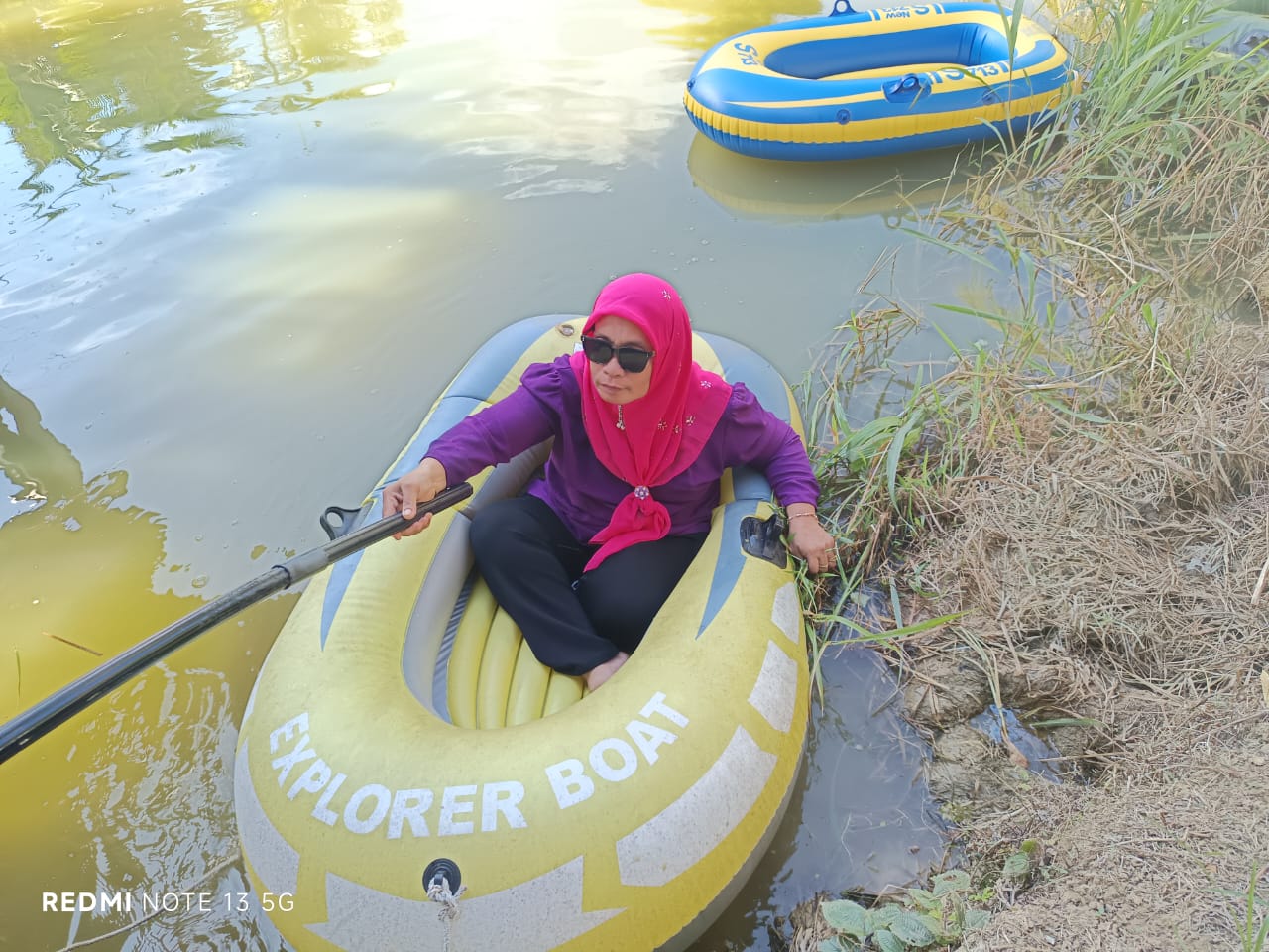 Visitor paddling inflatable Explorer Boat on the farm pond
